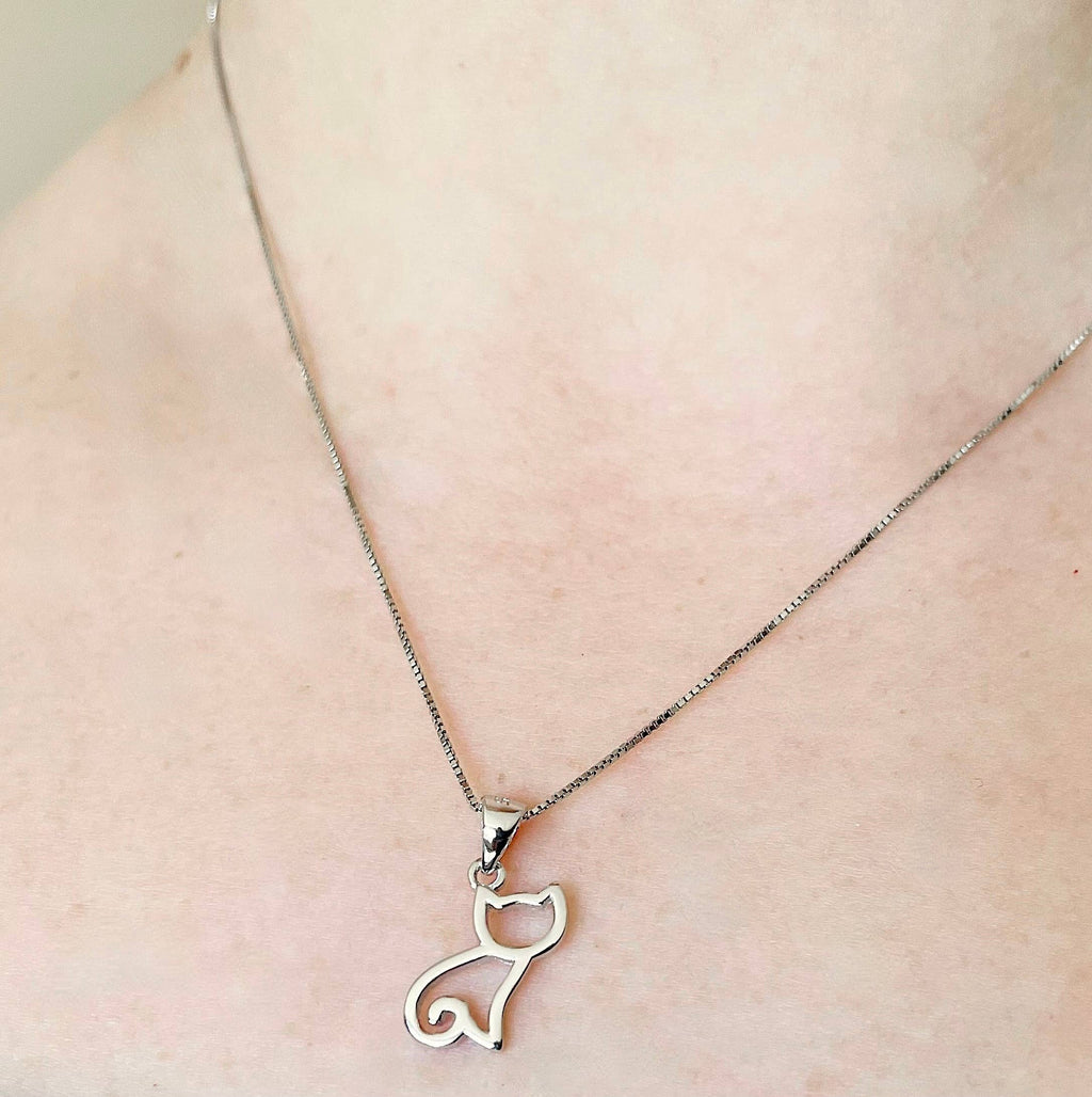 Cat-shaped pendant necklace on a person's neck against a neutral background