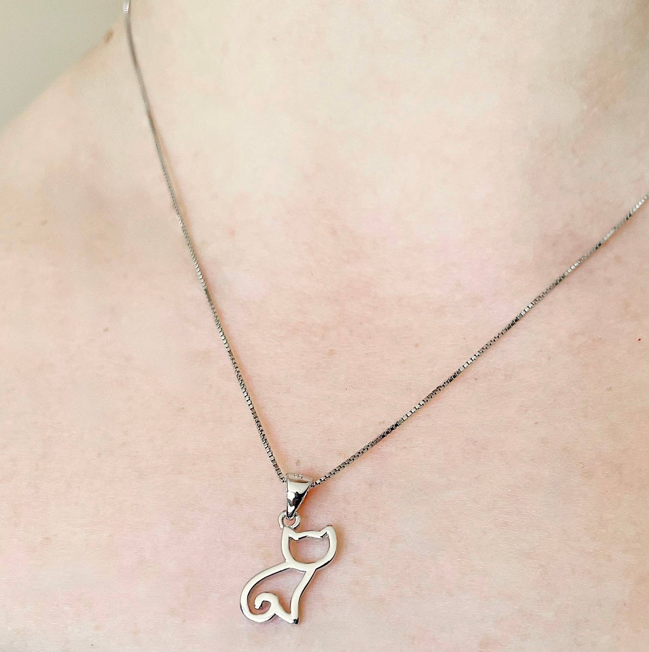 Cat-shaped pendant necklace on a person's neck against a neutral background