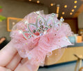 Pink decorative bow with rhinestones held in a hand against a blurred indoor background
