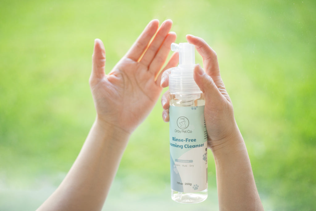 Person holding a bottle of 'None Toxic' cleaning cleaner with a blurred green background