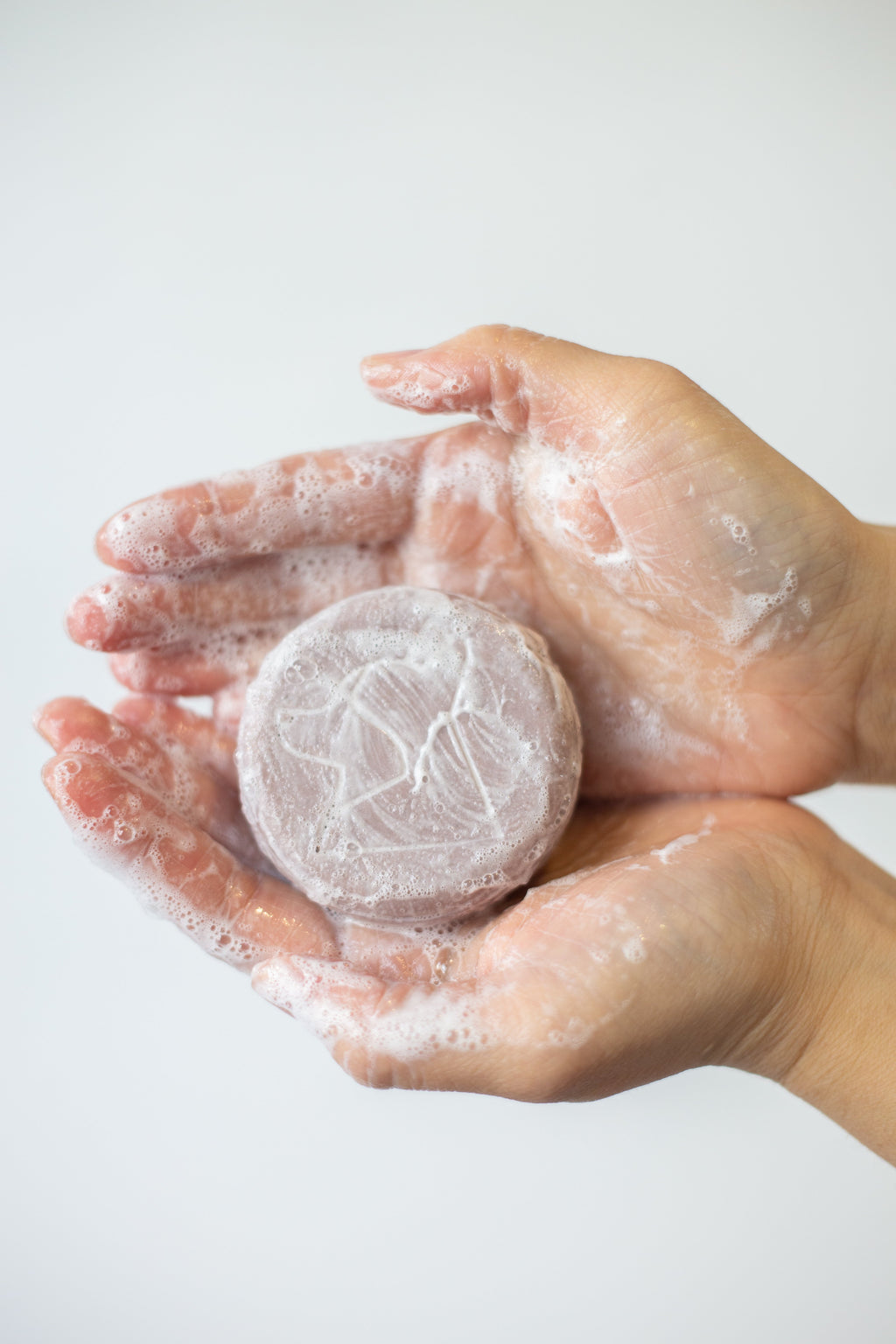 Hand holding a round, white, textured object against a light background