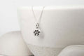 Silver paw print necklace on a white ceramic dish