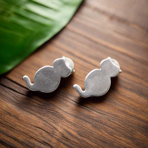 Silver cat stud earrings displayed on wooden surface